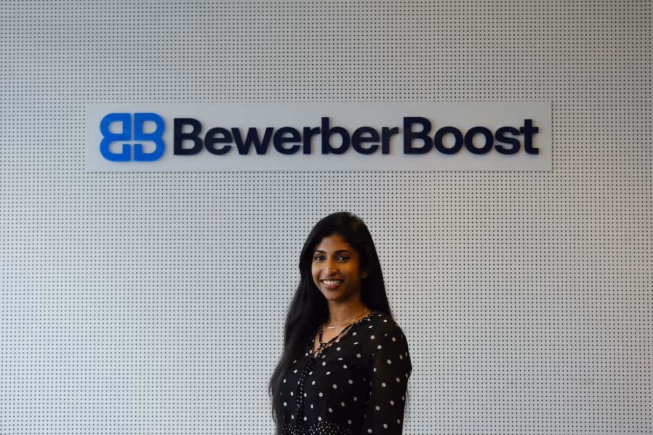 Nilaanthy, HR Managerin, vor der Wortmarke im Büro von BewerberBoost