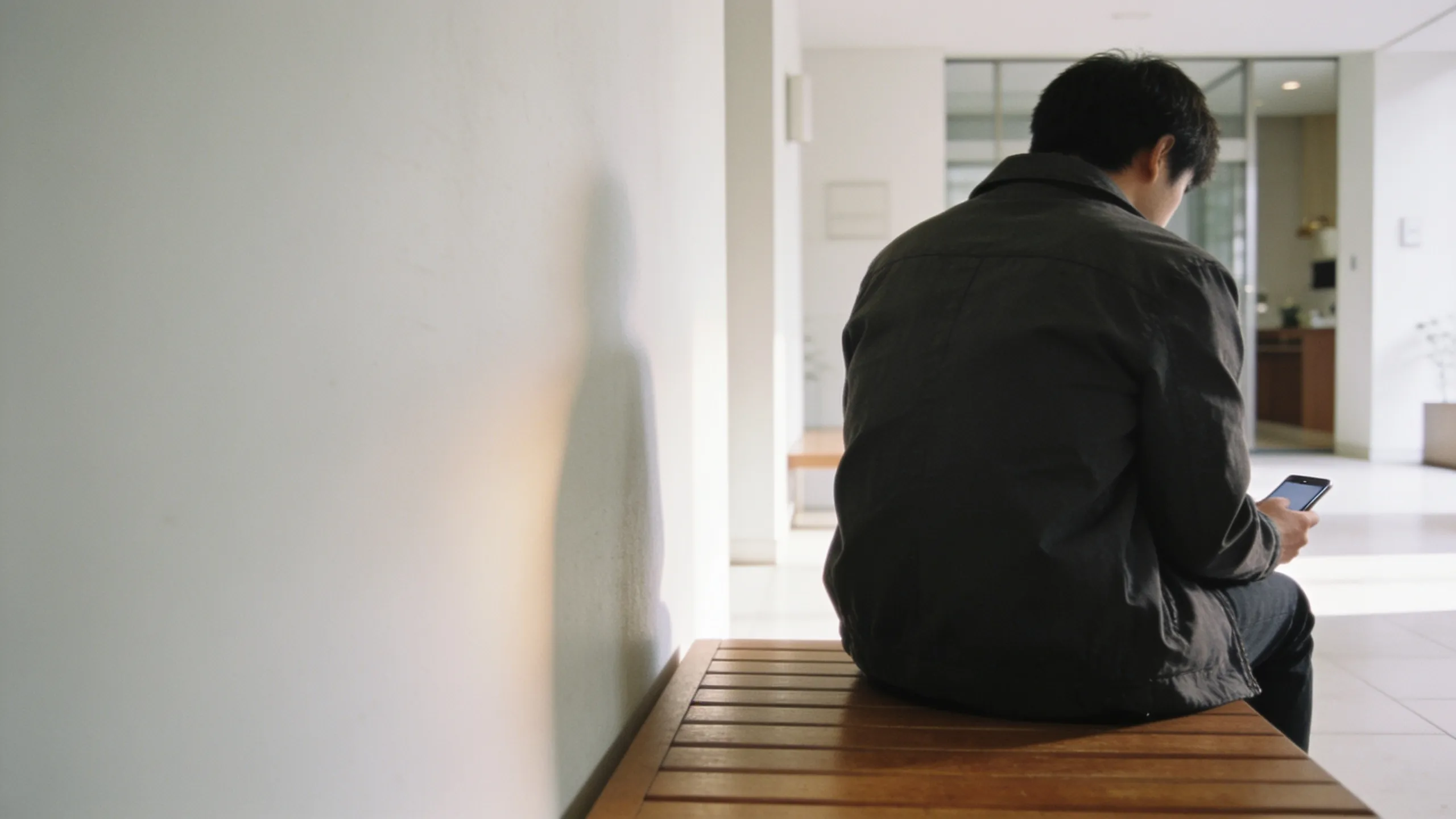 Person auf einer Bank, Telefon in der Hand