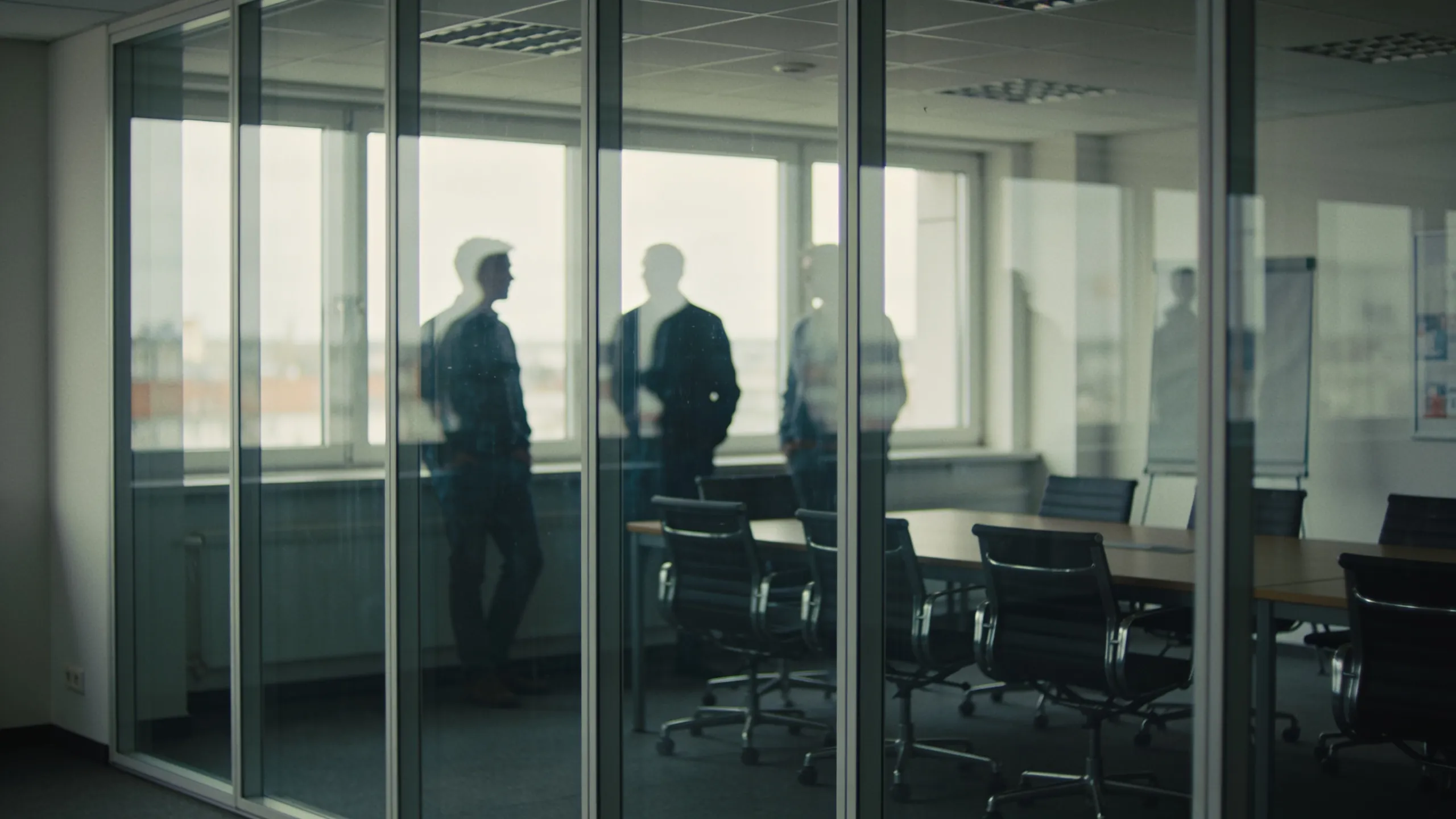 Besprechungsraum hinter einer Glaswand, Silhouetten am Tisch